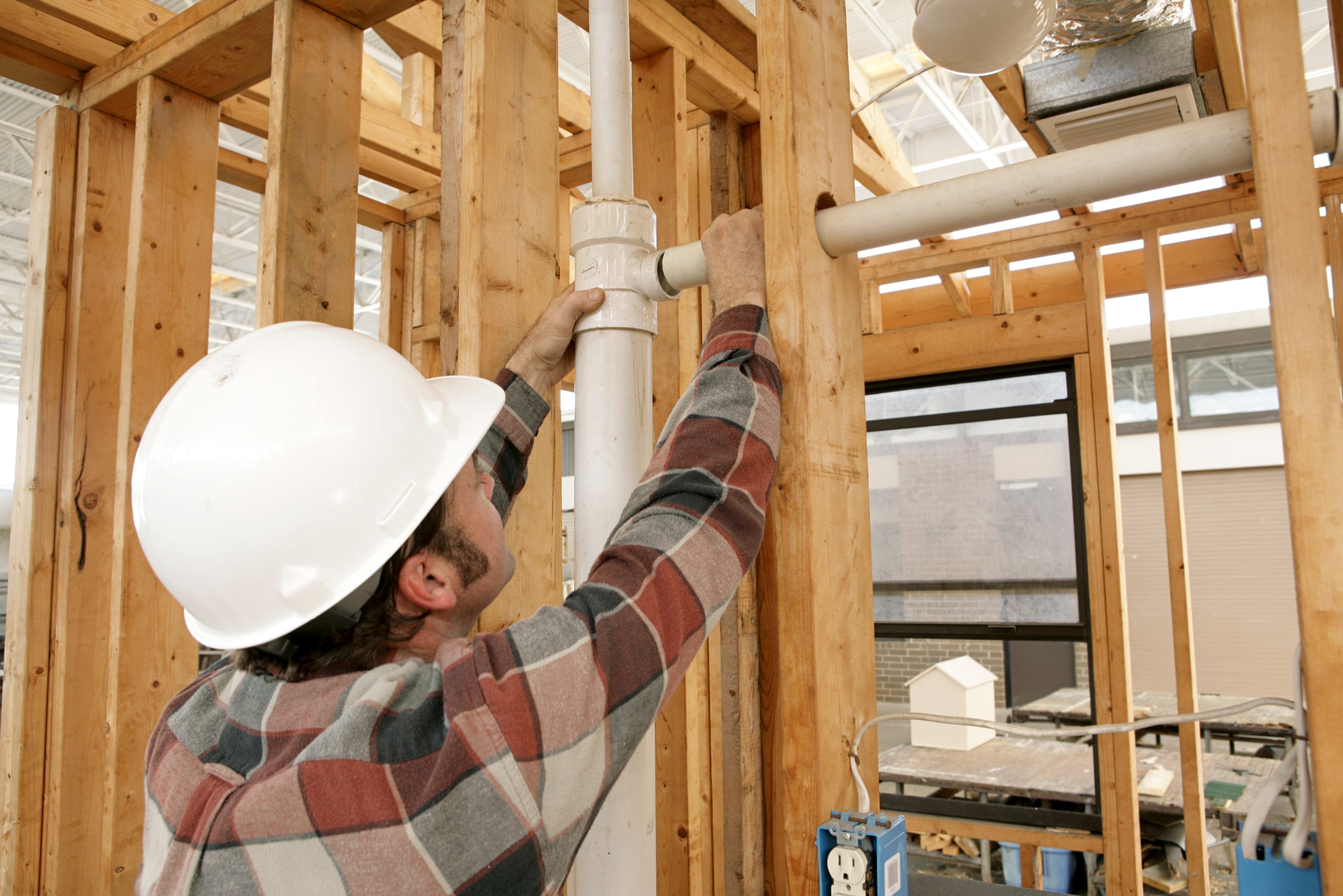 Construction Worker Installing Radon Mitigation System in New Building
