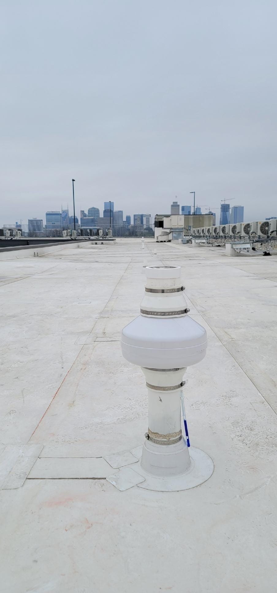 Radon mitigation system on rooftop with city skyline in background