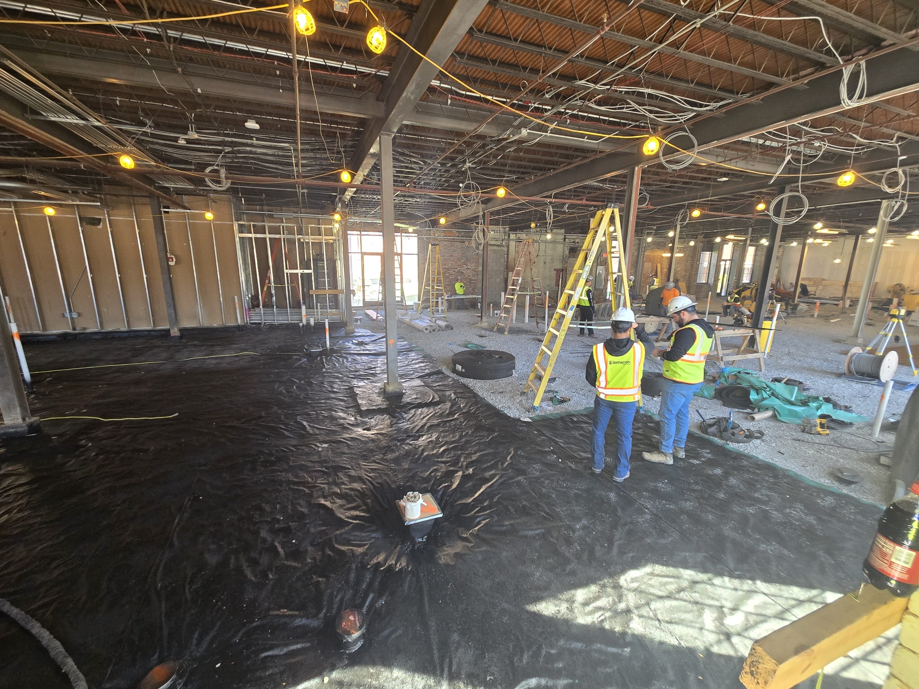 Construction workers installing vapor barrier in building under renovation
